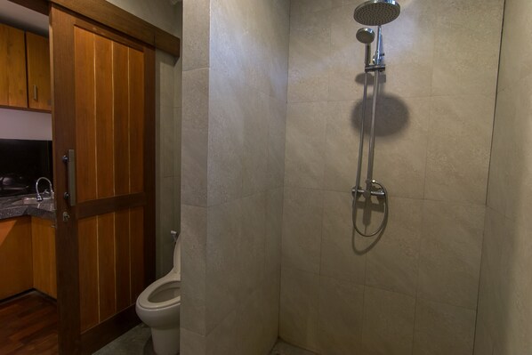 A bathroom with a shower, toilet, and wooden cabinets.