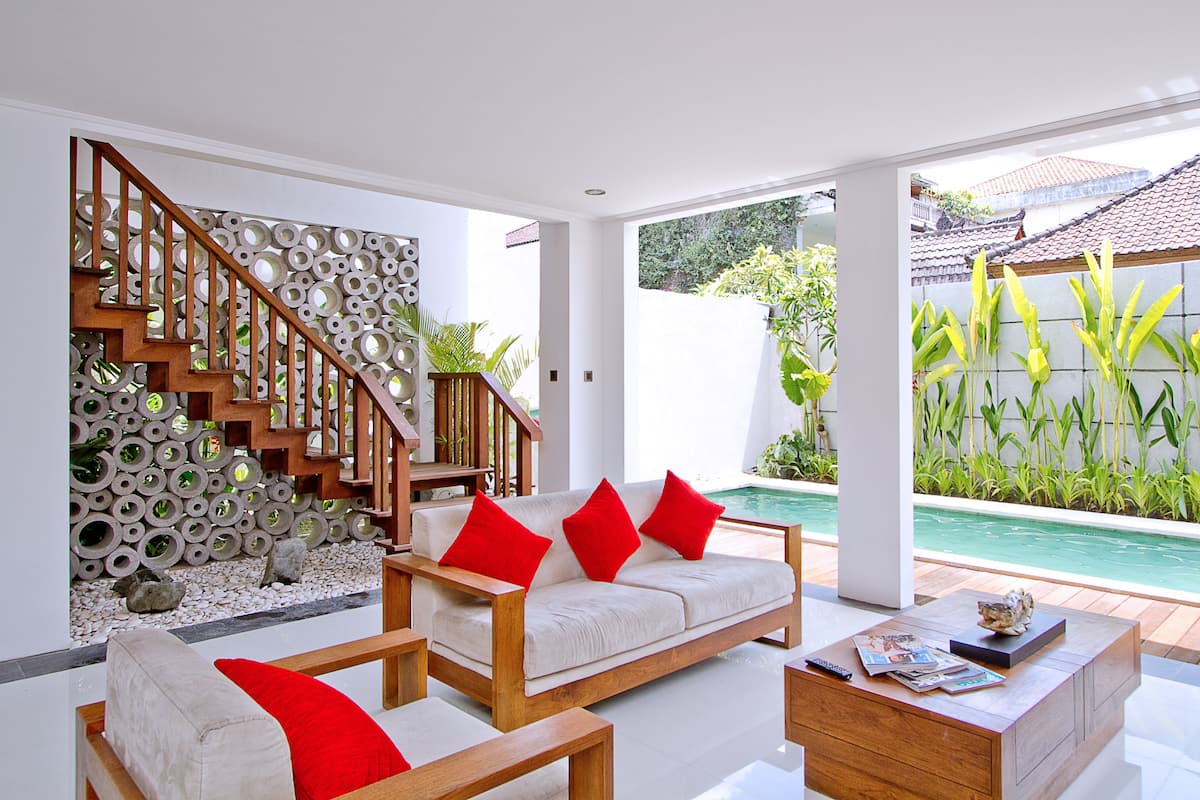 A modern living room with a sofa, coffee table, and a staircase with a unique circular design.