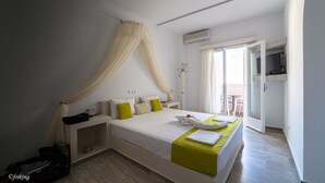 Un dormitorio con cama, mesita de noche, maleta y ventana con cortinas.