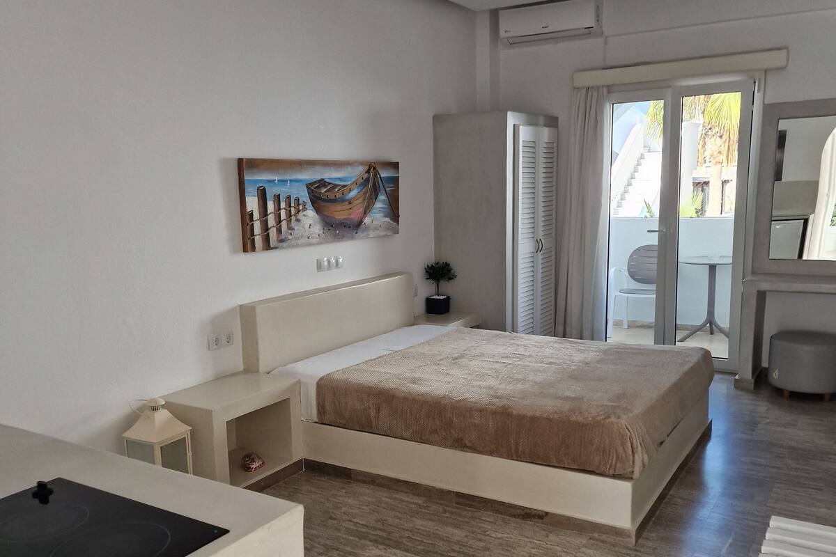 Un dormitorio moderno con una cama grande, una mesita de noche pequeña, un calentador incorporado y vistas al balcón.