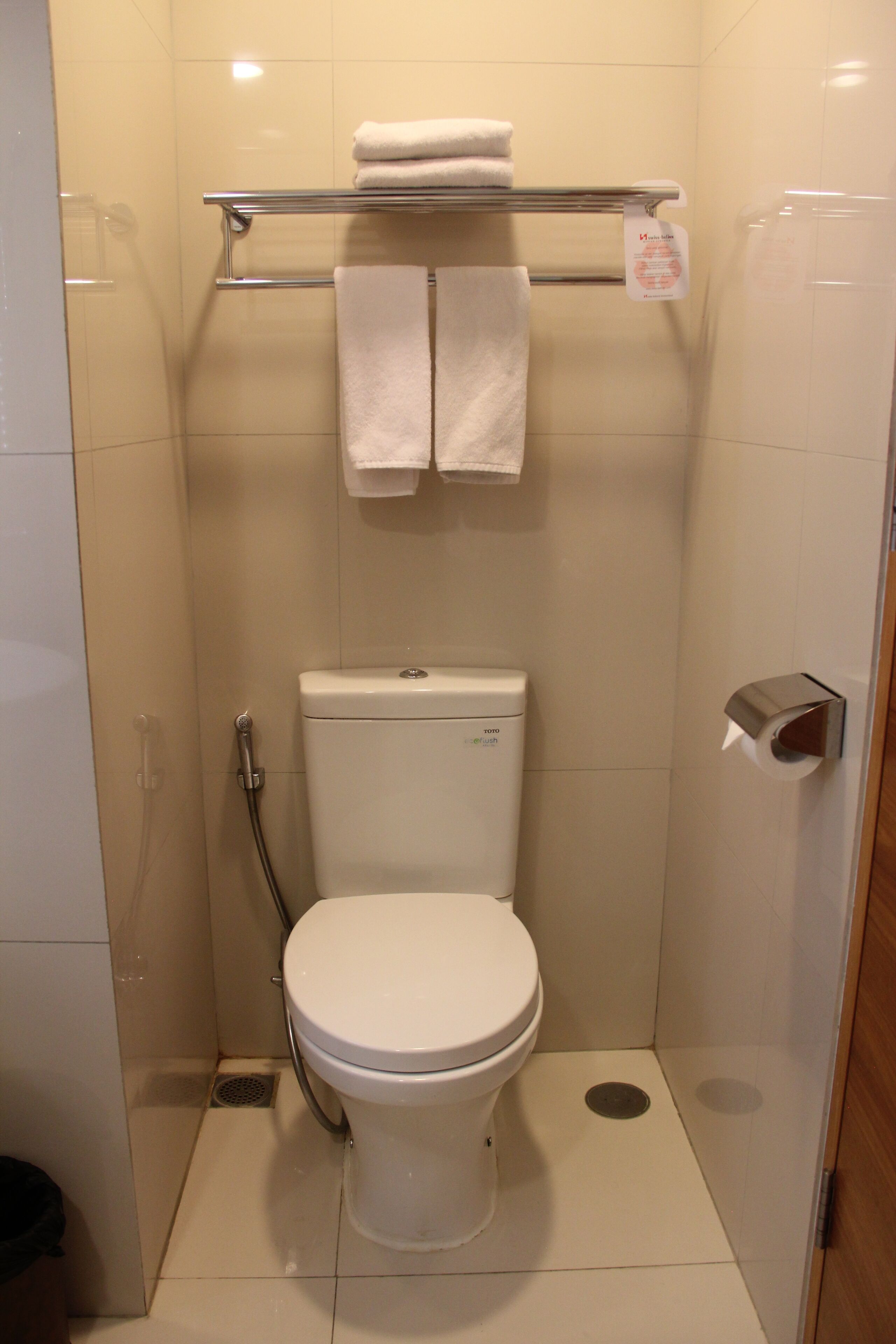 A small, modern bathroom with a toilet, a shower, and a towel rack.