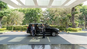 A black SUV parked in a spacious, well-lit area with a modern ceiling design and lush greenery in the background. - Swiss-Belinn Manyar (Surabaya)