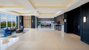 A spacious lobby with a modern design, featuring a sofa set, a coffee table, and a seating area with a view of the cityscape. - Swiss-Belinn Manyar (Surabaya)