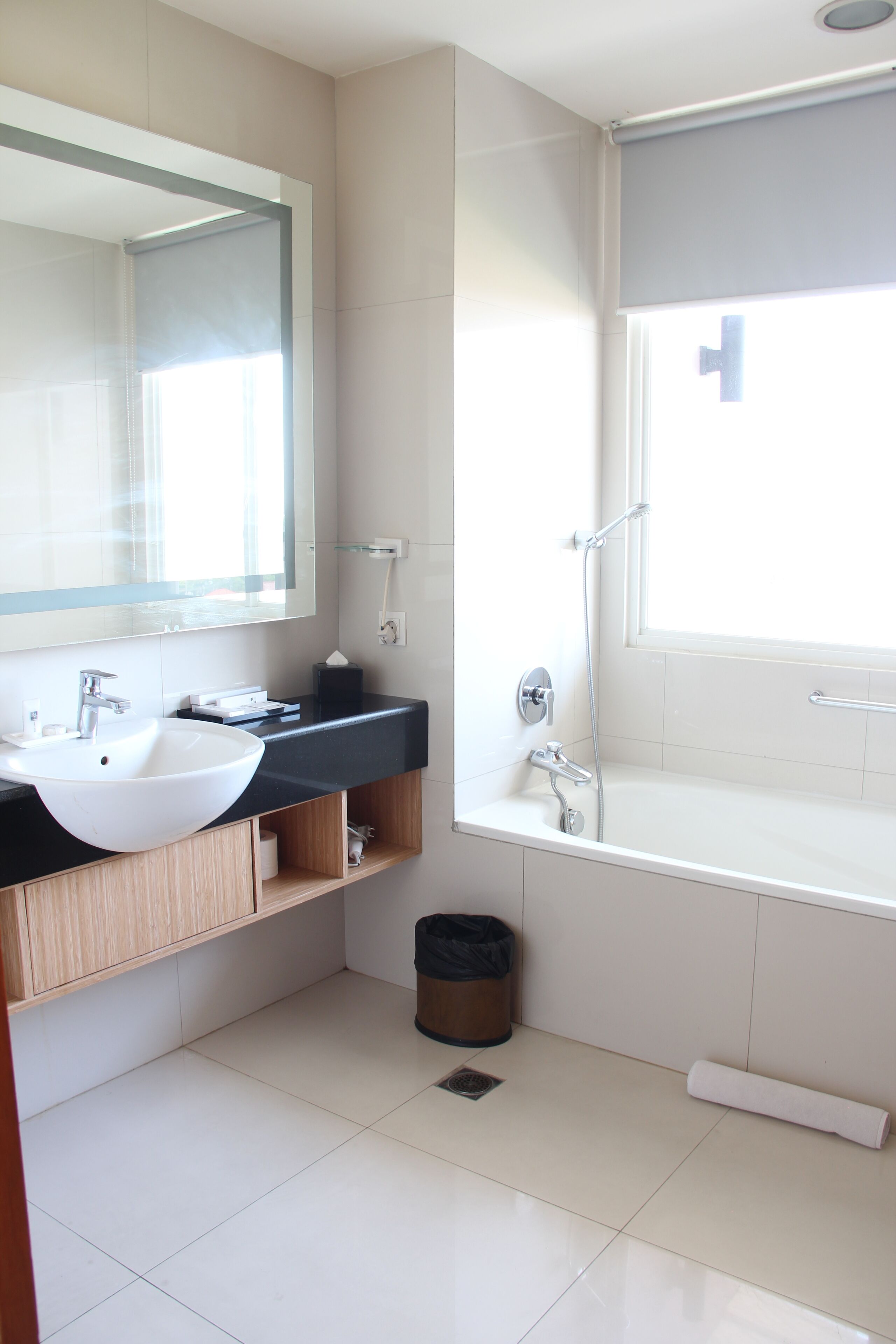 A modern bathroom with a white sink, dark countertop, and a large mirror.