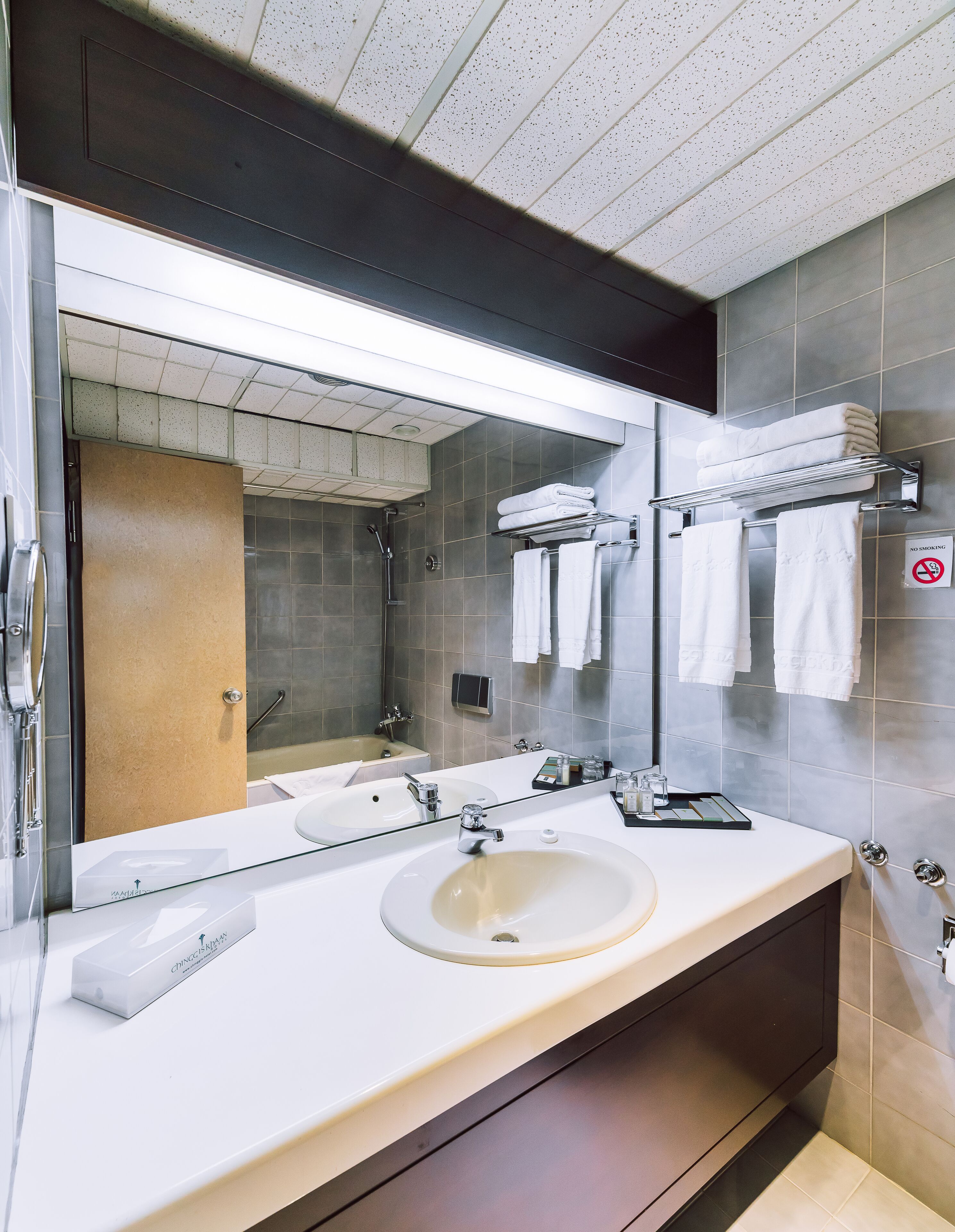 Un baño moderno con dos lavamanos, un espejo grande y una zona de ducha.