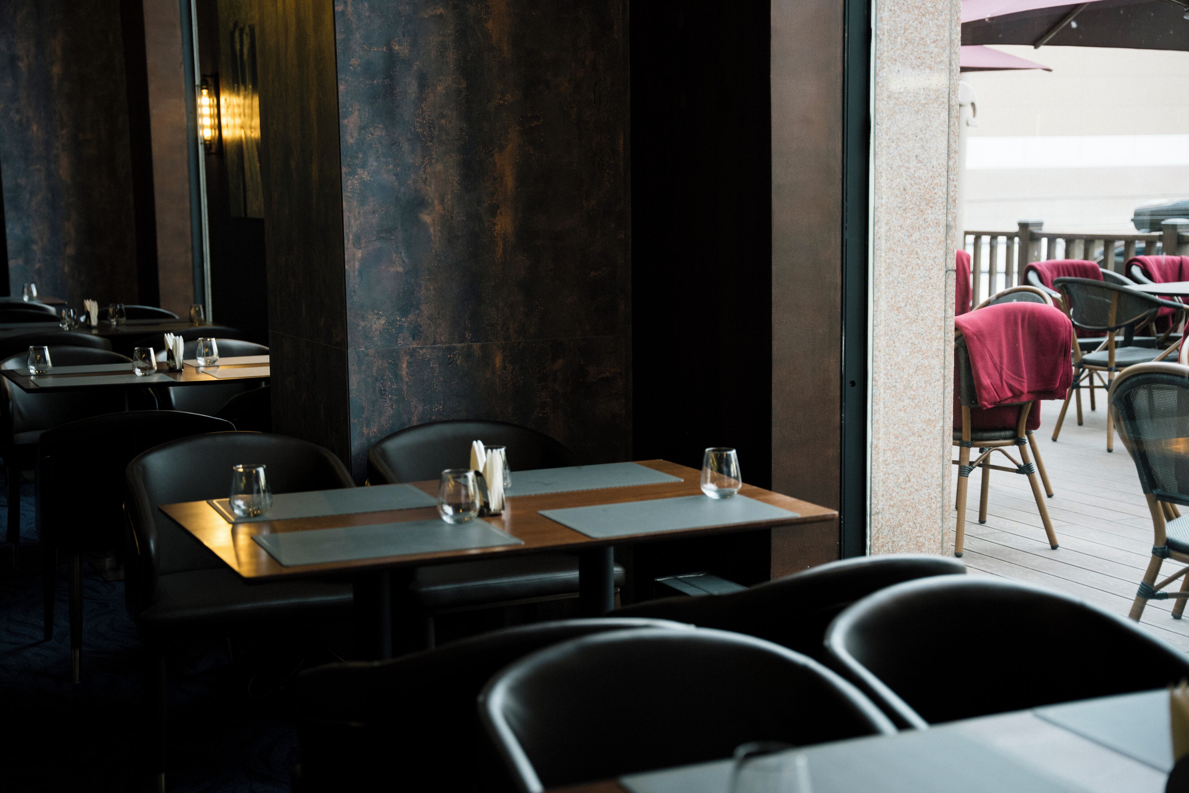 An indoor dining area with tables and chairs, a view of the outdoor seating area, and a large mirror on the wall.