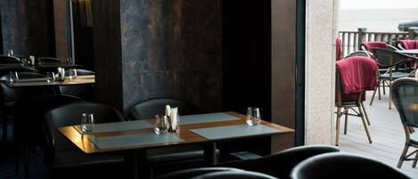 An indoor dining area with tables and chairs, a view of the outdoor seating area, and a large mirror on the wall.