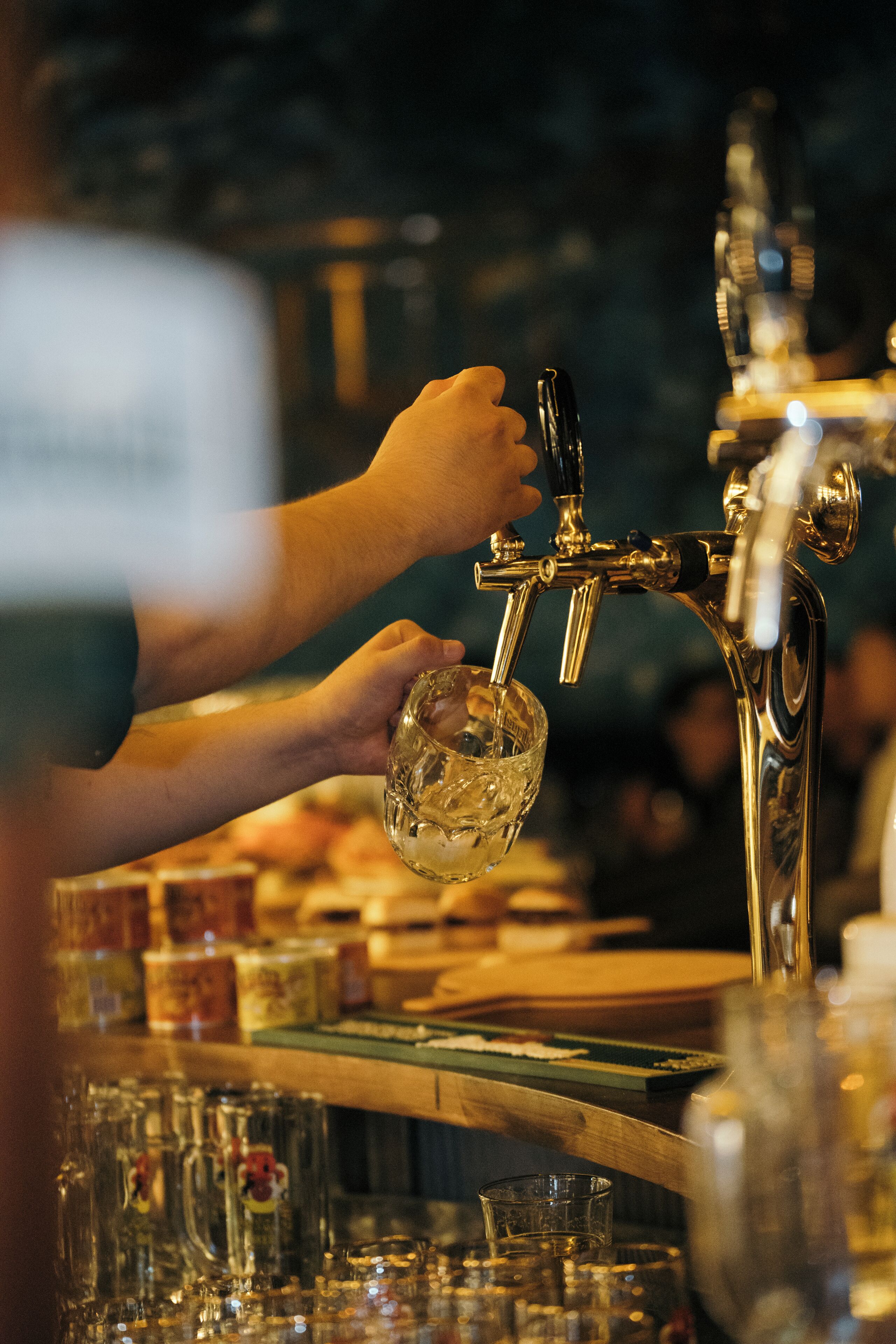 A hand filling a glass at a bar tap.