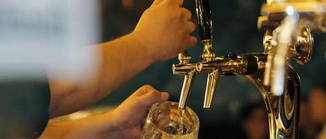 A hand filling a glass at a bar tap.