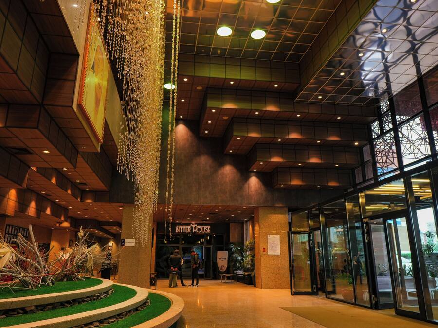 Un vestíbulo con una columna central, una cafetería llamada 'Bitter House' y una entrada de vidrio.