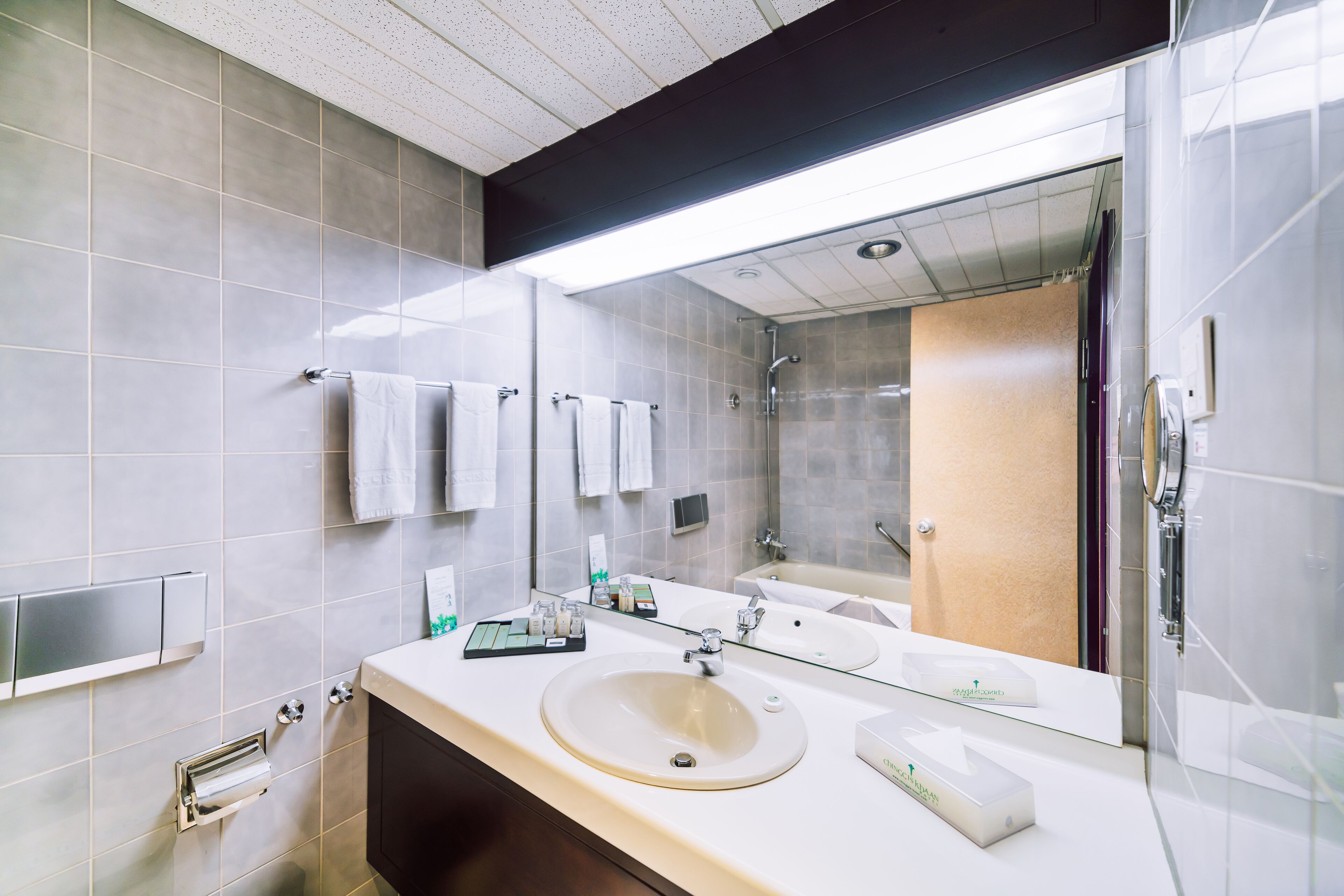 Un baño moderno con un espejo grande, un lavabo y una zona de ducha.