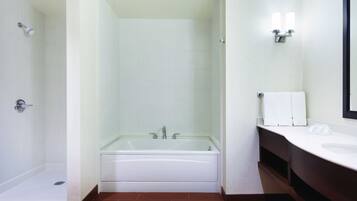 A modern bathroom with a glass-enclosed shower, a white bathtub, and a vanity with a mirror.