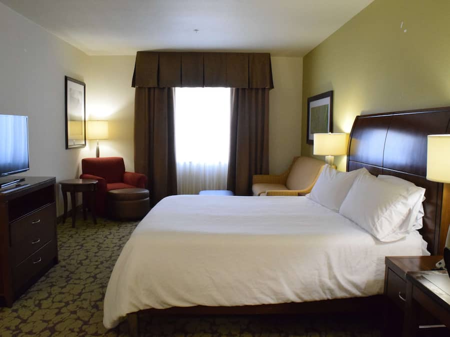 Quarto de hotel com uma cama grande, televisão, escrivaninha e uma cadeira.