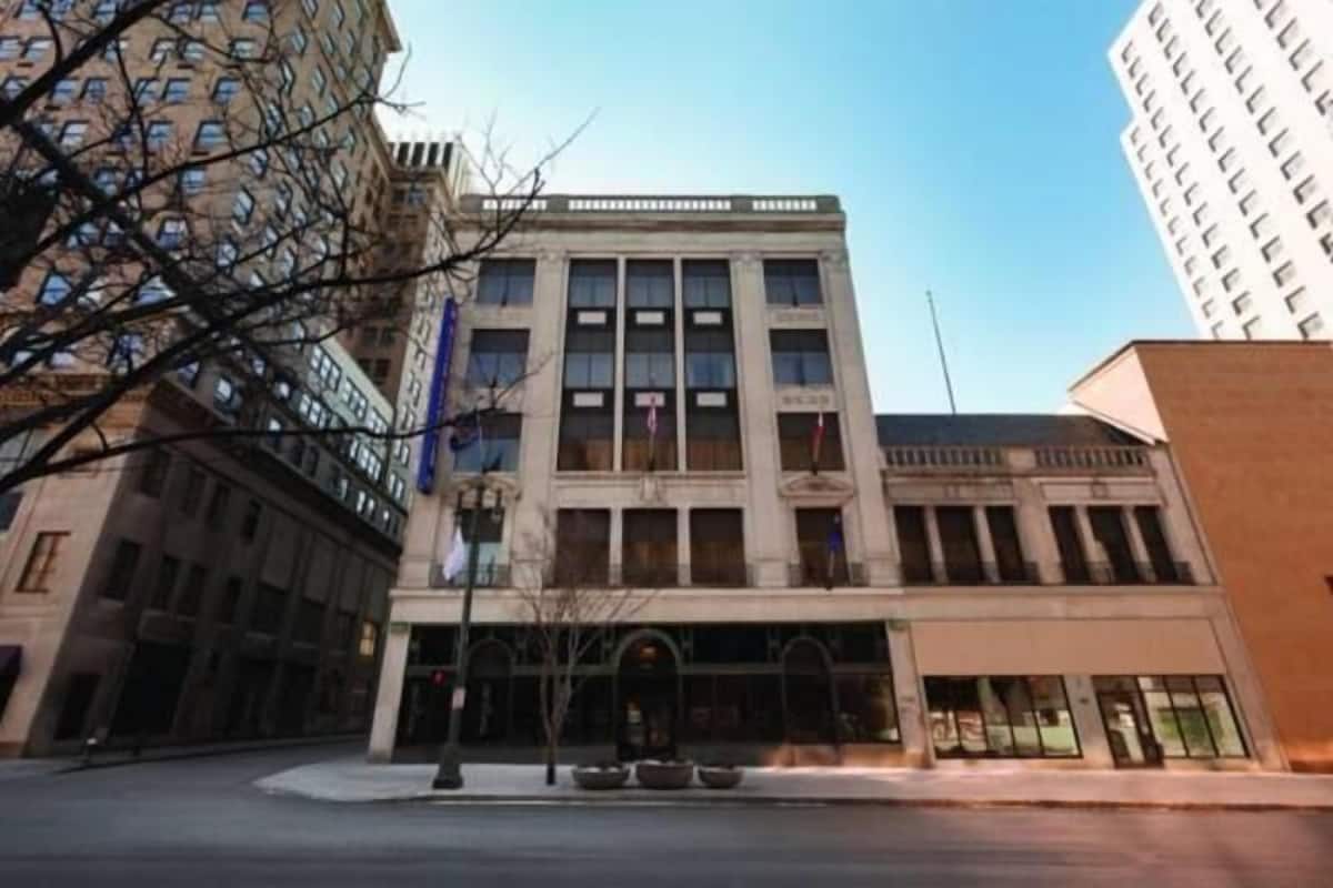 A multi-story building with a central entrance, large windows, and a flat roof.