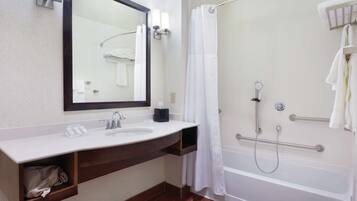 A modern bathroom with a white sink, mirror, and shower area.