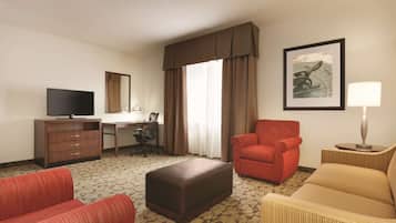 Een hotelkamer met een bed, een bureau, een stoel, een televisie en een lijst met een afbeelding aan de muur.
