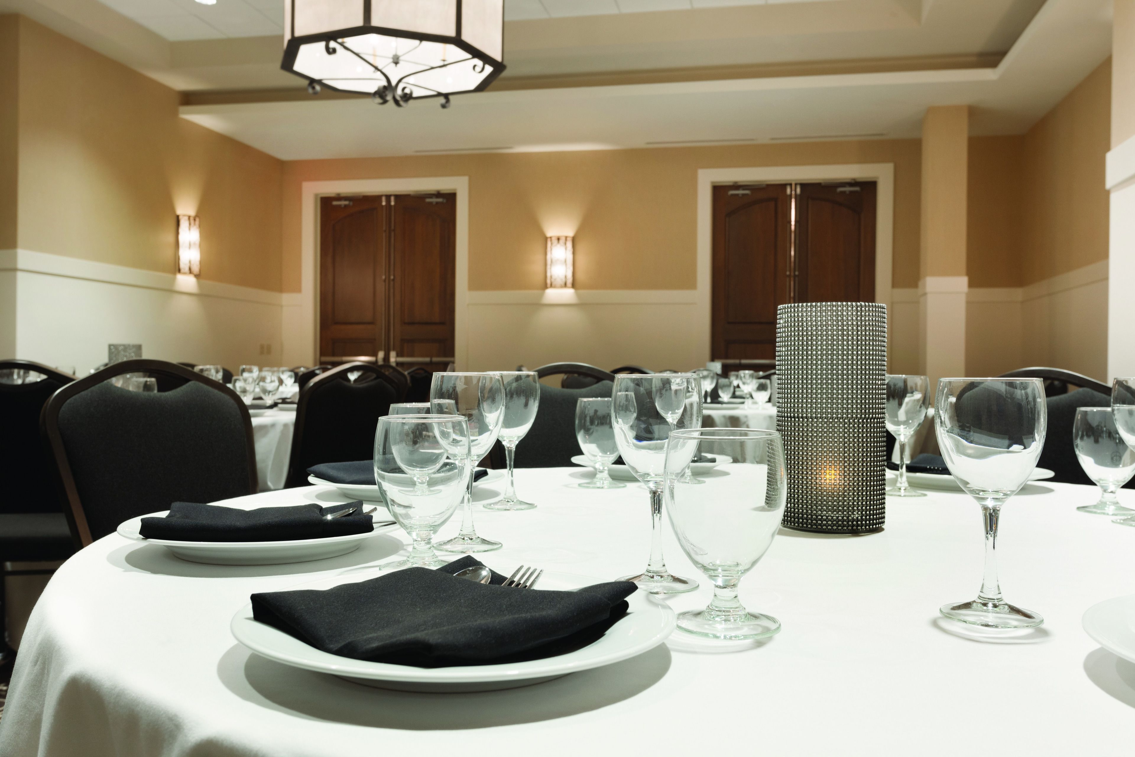 A dining area with round tables set for a meal, each with plates, cutlery, and wine glasses.