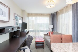 Une chambre d’hôtel équipée d’un bureau, d’une télévision, d’un canapé et offrant une vue sur l’extérieur.