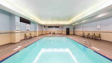A large indoor swimming pool with multiple lanes, lounge chairs, and a no diving sign on the wall.