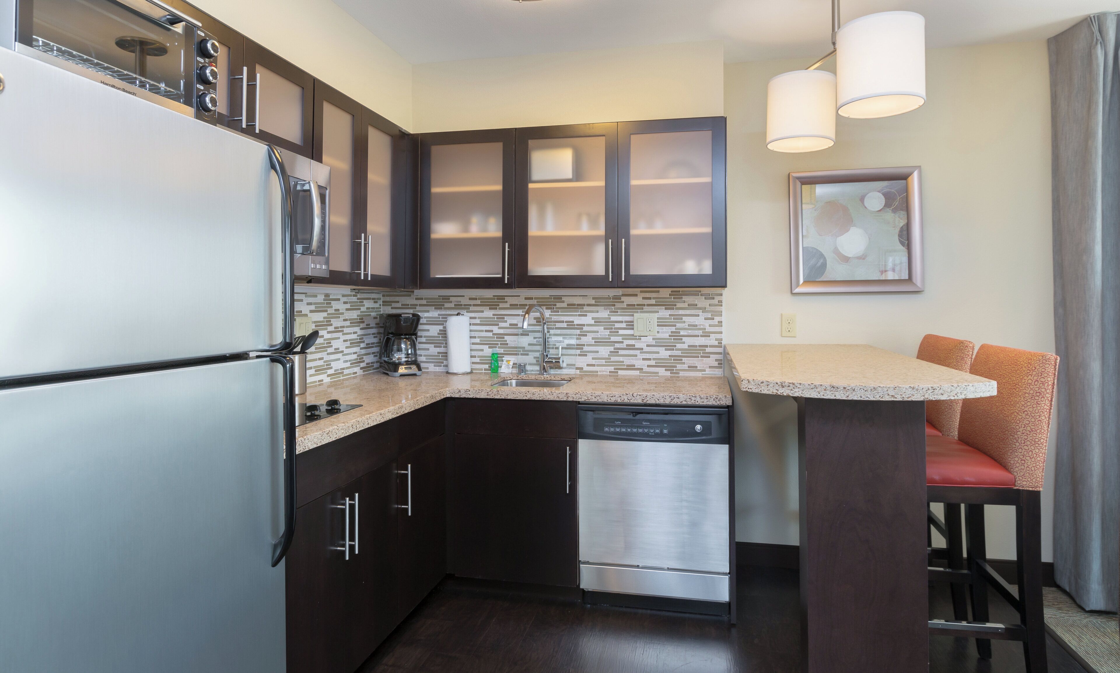A compact kitchen with a refrigerator, dishwasher, and a coffee maker.