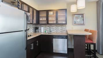 A compact kitchen with a refrigerator, dishwasher, and a coffee maker.