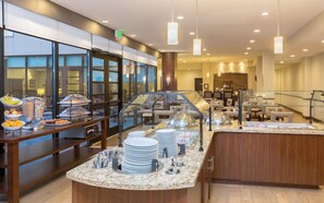 Un espace buffet proposant une variété de plats, une vitrine réfrigérée et un coin salon avec des tables et des chaises.