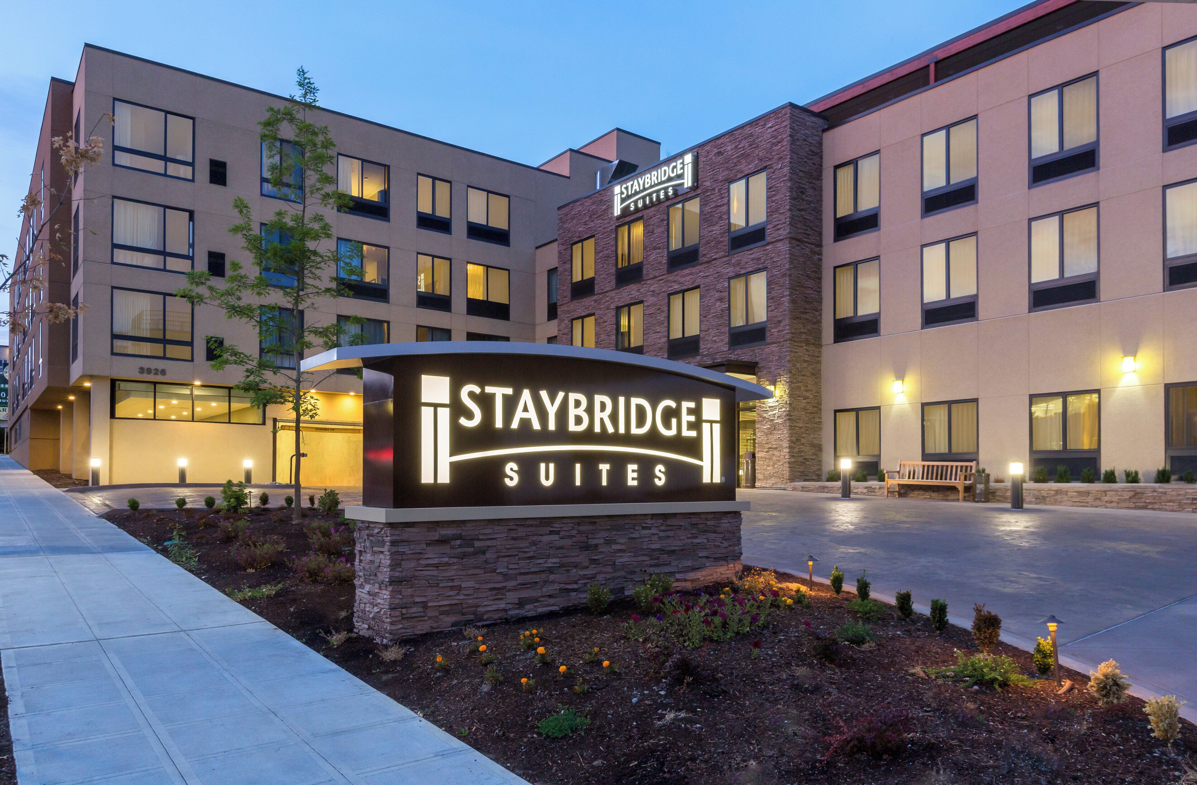 Un letrero de Staybridge Suites con un edificio moderno al fondo.