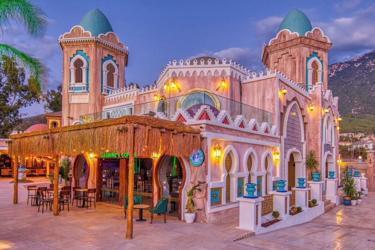 A traditional building with two domed towers, a covered seating area, and a shop named "Jasmine's Coz."