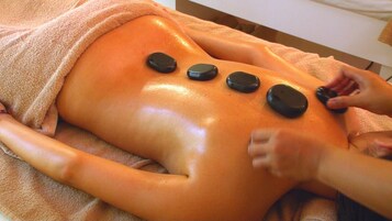 A person receiving a stone massage with four stones placed on their back.