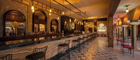 A bar area with a long counter, multiple seating options, and a patterned floor.