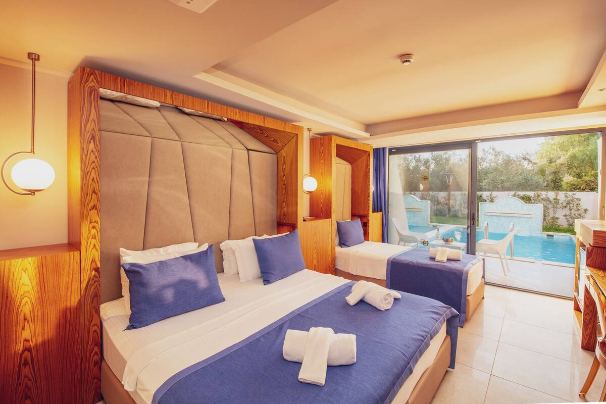 Une chambre d’hôtel avec deux lits, une grande fenêtre et vue sur une piscine.