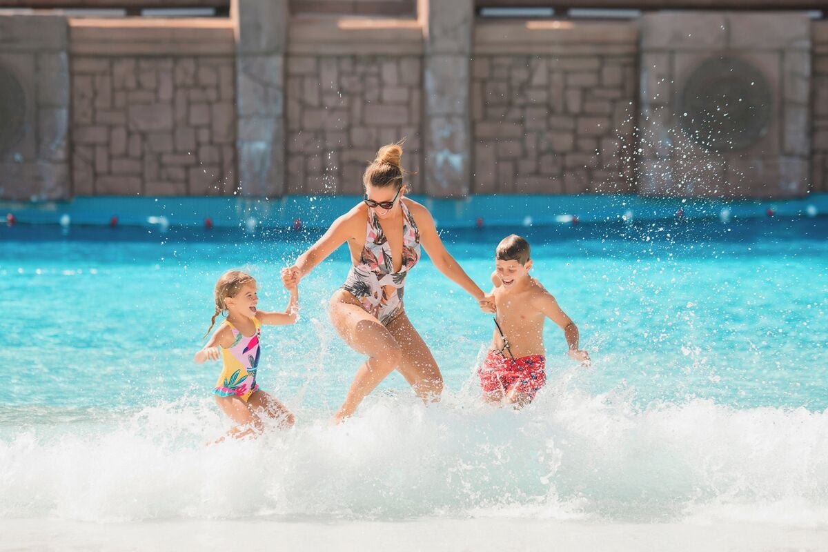 A pool area with a stone wall and a clear blue pool.