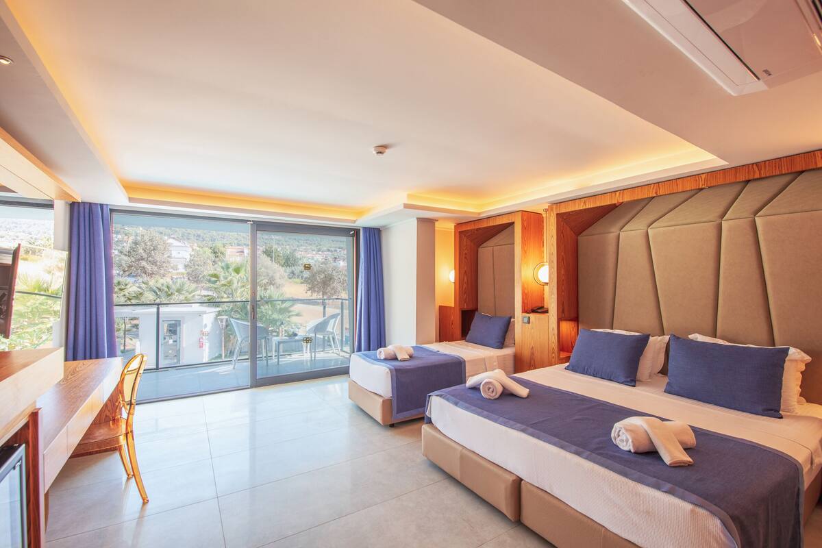 Une chambre d’hôtel avec deux lits, un bureau et un balcon offrant une vue.