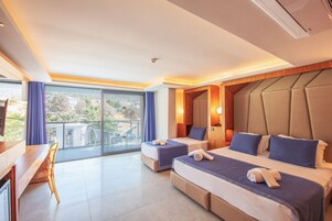Habitación de hotel con dos camas, un escritorio y un balcón con vistas.