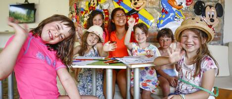 A group of children seated at a table with Mickey Mouse decorations in the background.
