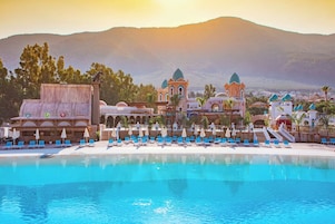Un resort con piscina, sillas de descanso y un edificio con techos abovedados.