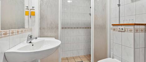 Un baño con lavamanos blanco, inodoro y cabina de ducha.