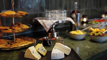Un bufé con queso, frutas y vasos sobre una encimera de mármol.