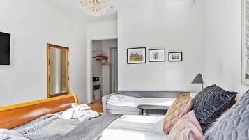 Une chambre à coucher avec un lit, une table de chevet et un miroir. Trois tableaux encadrés sont accrochés au mur.