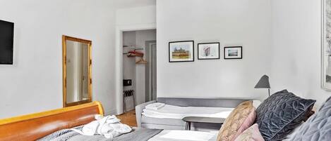A bedroom with a bed, bedside table, and a mirror. There are three framed pictures on the wall.