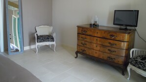 Una habitación con un aparador de madera, una silla, un televisor sobre un mueble bajo y un cuadro enmarcado en la pared.