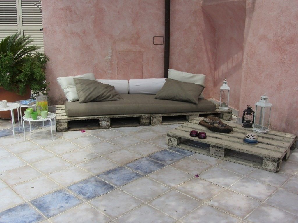 A cozy outdoor seating area with a wooden bench and a cushioned bench against a pink wall.