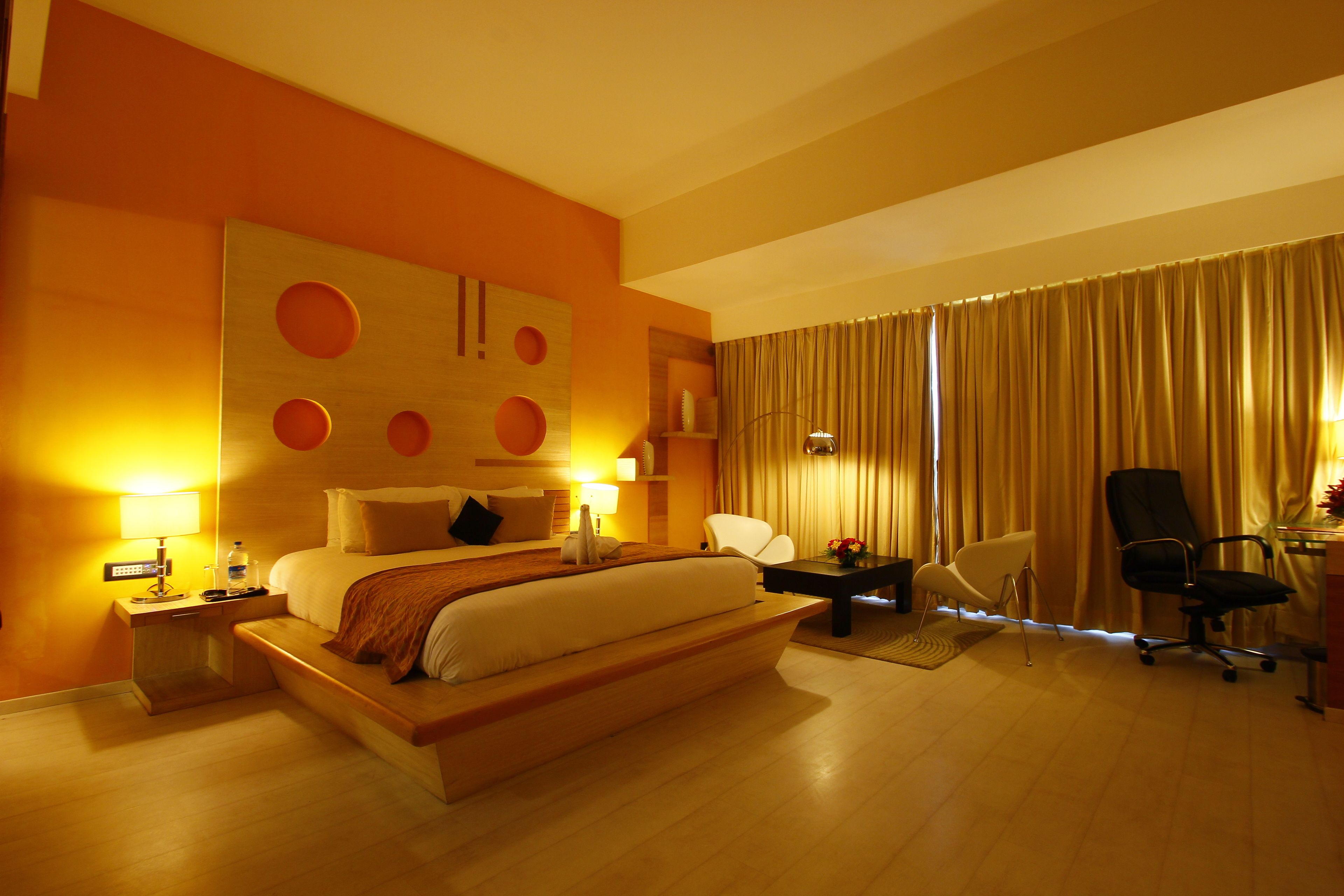 A hotel room with a large bed, bedside tables, a desk, and a chair.