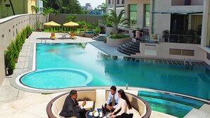 A poolside area with a circular pool, lounge chairs, and a seating arrangement for three people. - Grand Estancia (Salem)