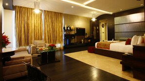 A modern hotel room with a large bed, a seating area with a table, and a TV. - Grand Estancia (Salem)