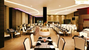A spacious dining area with multiple tables and chairs, a central dessert display, and a modern ceiling design. - Grand Estancia (Salem)