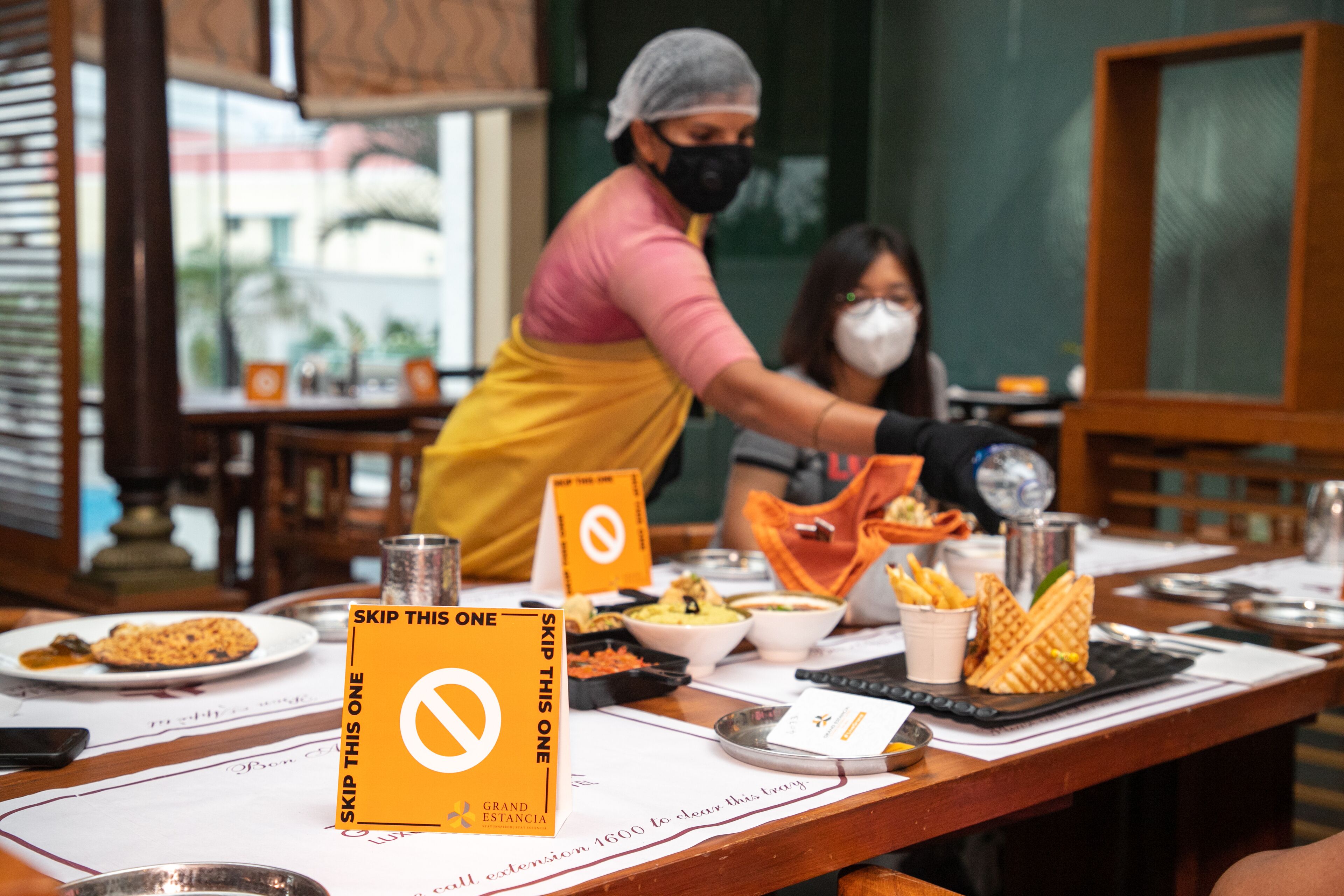 Un restaurante con una mesa de buffet, un cartel que dice 'Skip This One' y una persona sirviendo comida.