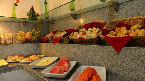 A buffet with various food items including bread, fruits, and sliced vegetables. - Alpha Praia Hotel (Fortaleza)