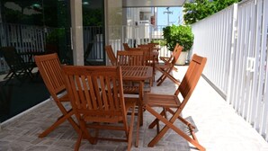 An outdoor patio with wooden furniture and a glass railing. - Alpha Praia Hotel (Fortaleza)