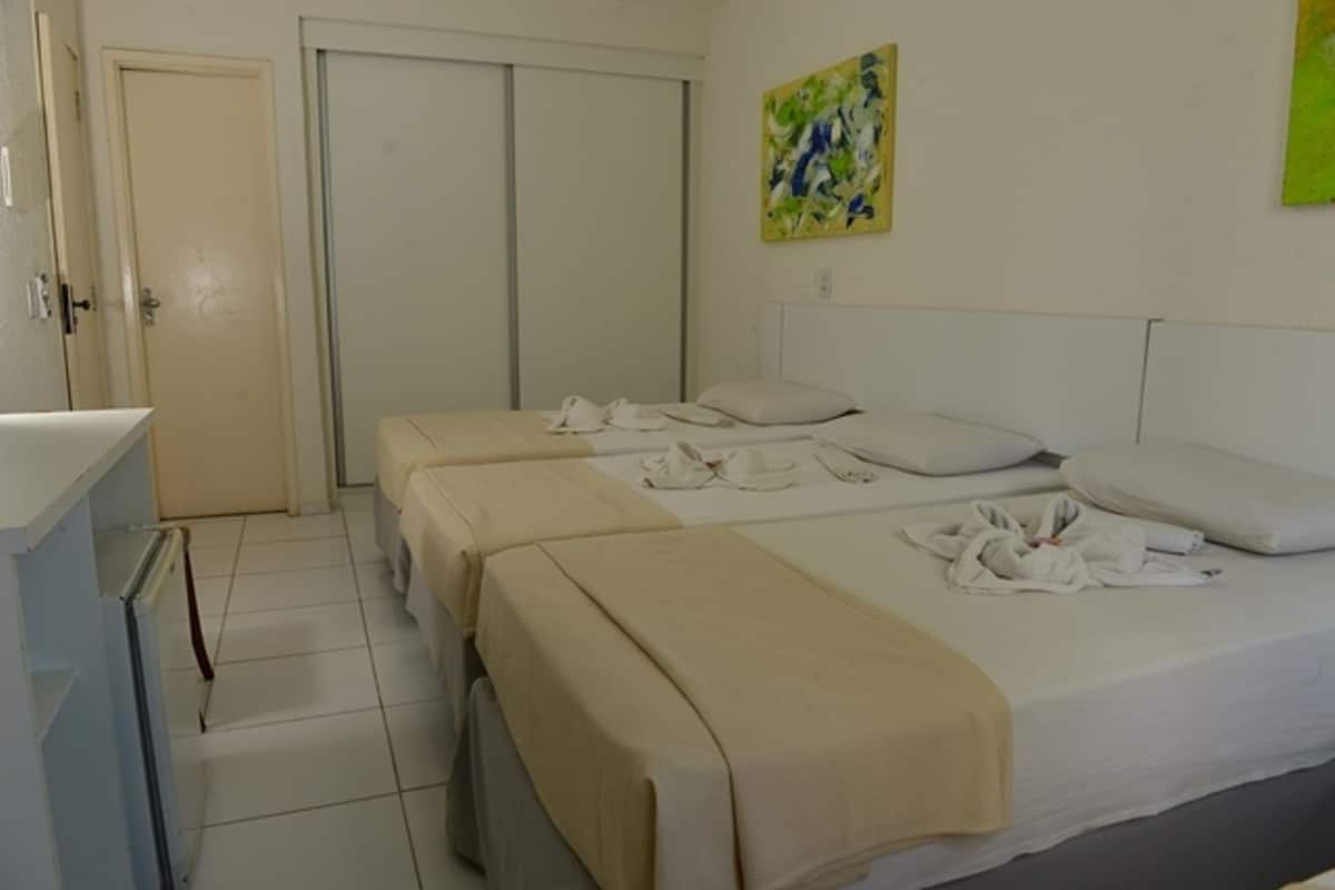 Una habitación de hotel con dos camas, un armario y un cuadro en la pared.